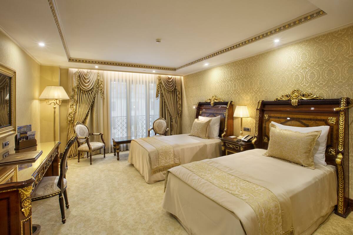 A hotel room with two beds, a desk, and a chair.