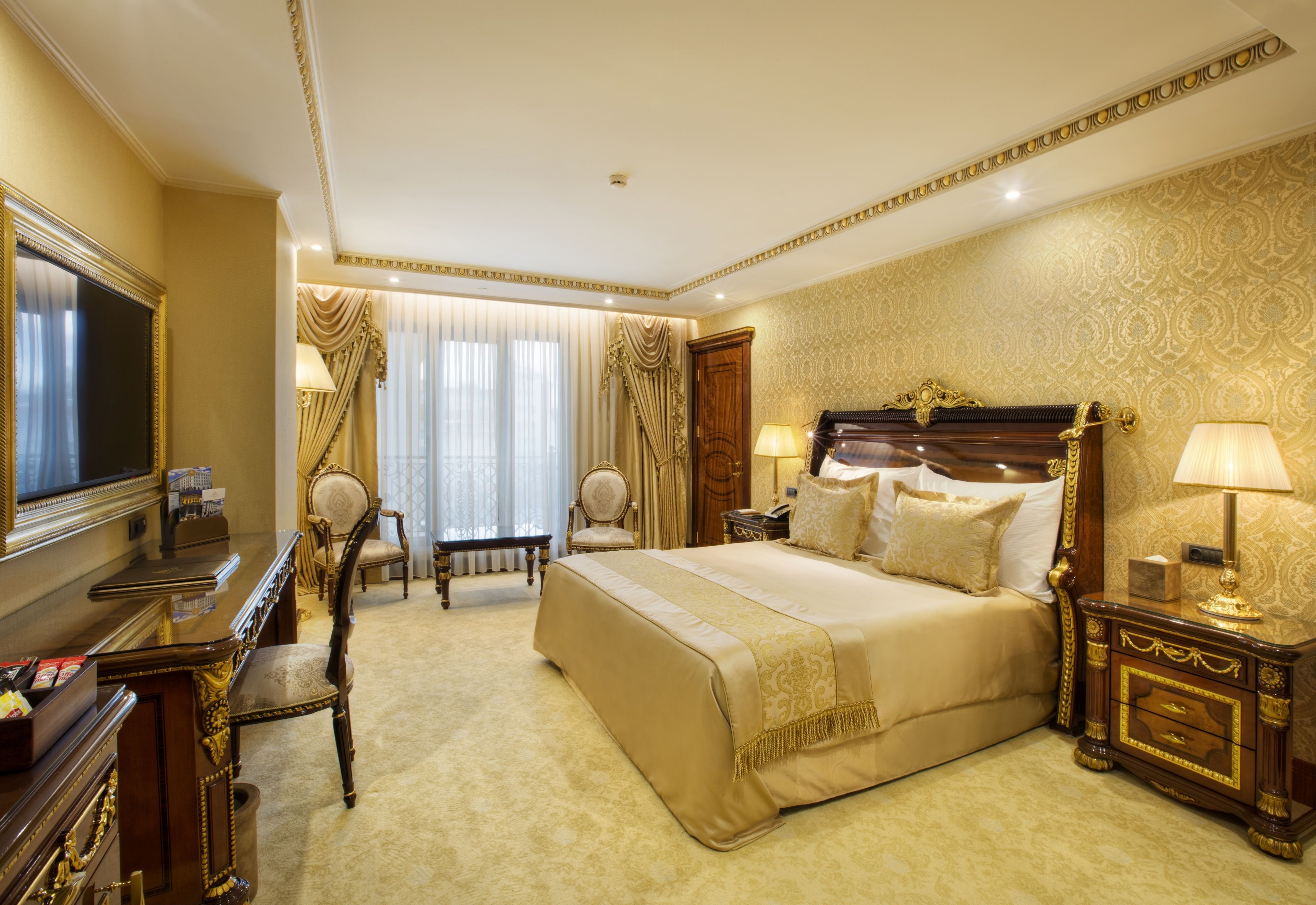 A luxurious hotel room with a large bed, a desk, and a television.