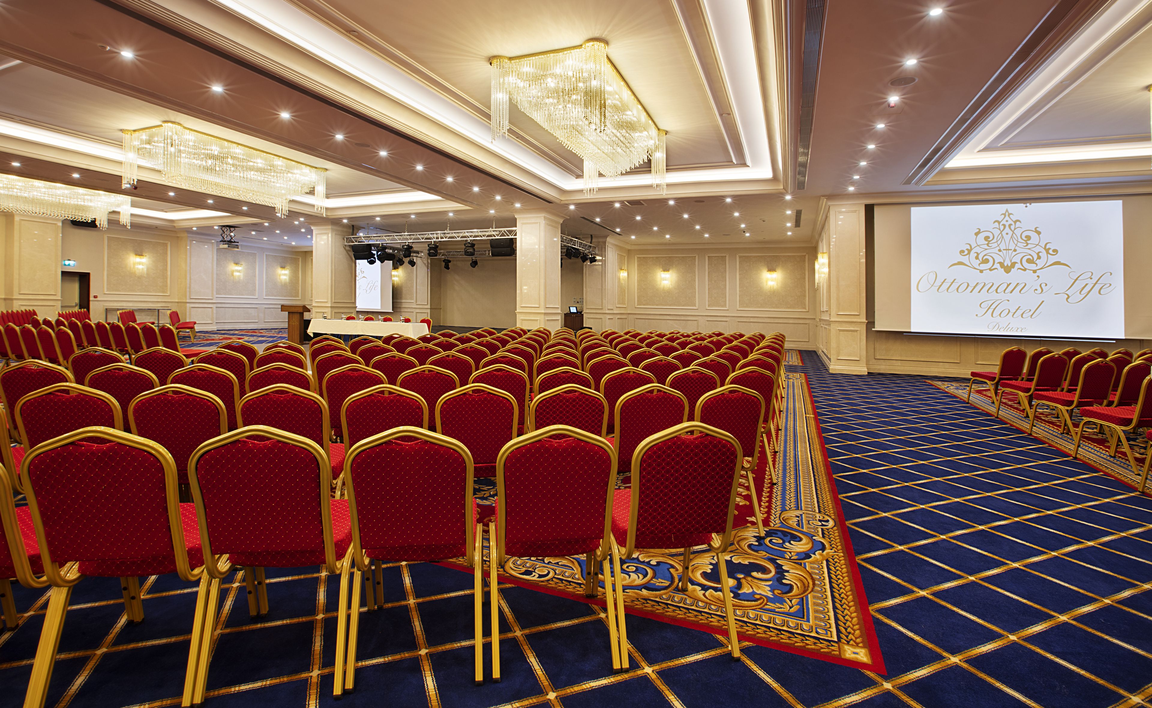 A conference room with rows of red chairs and a stage with a podium.