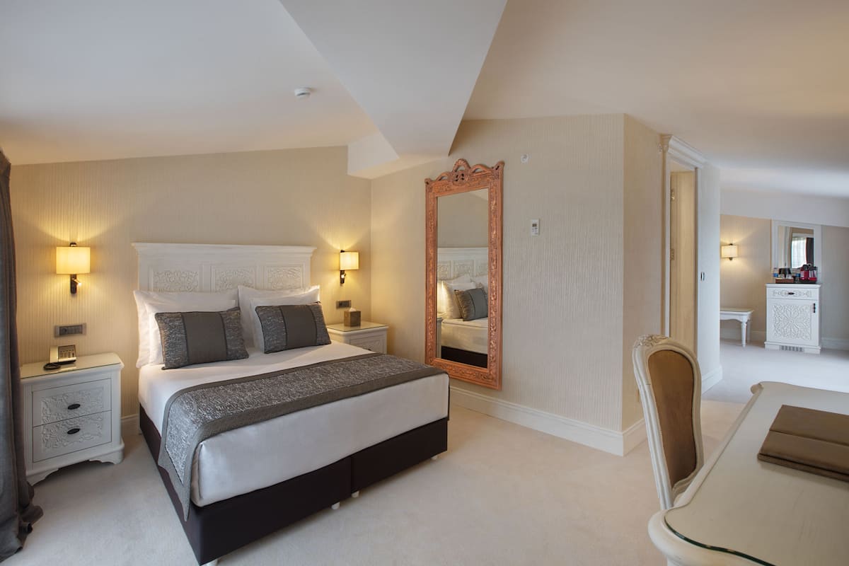 A bedroom with a bed, bedside tables, a mirror, and a chair.