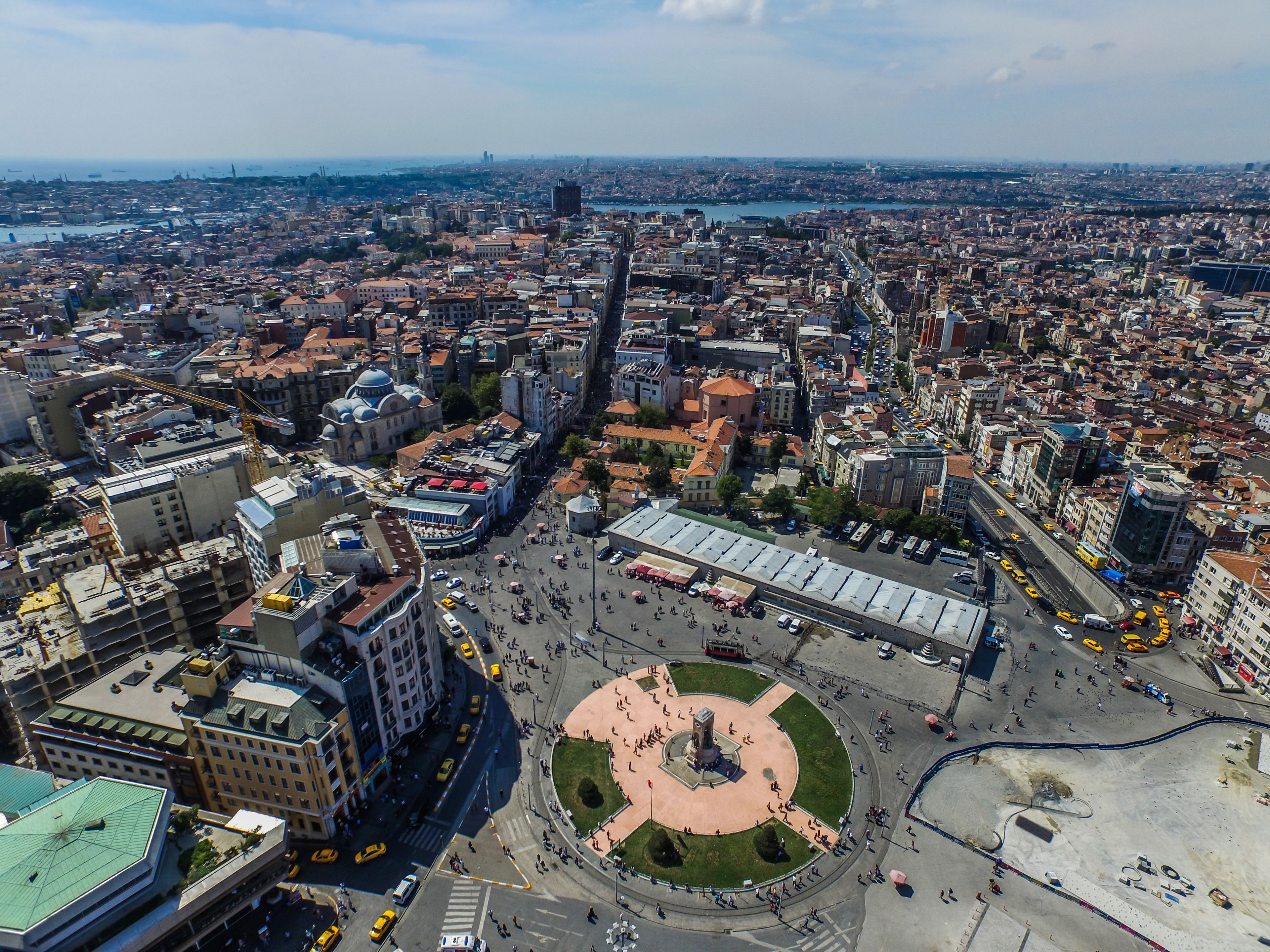 An aerial view of a cityscape with a prominent square, surrounding buildings, and a river in the background.