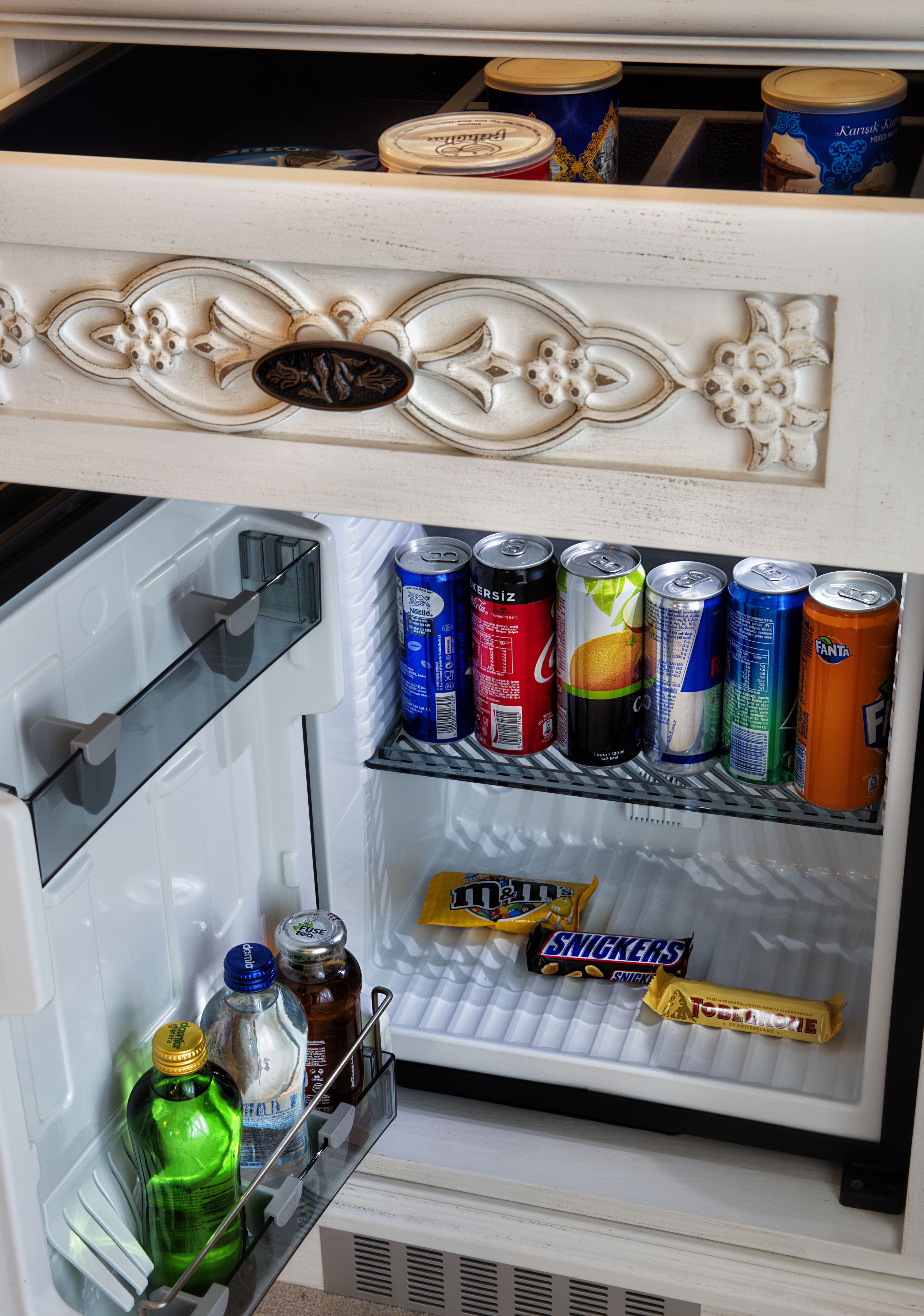 Un refrigerador pequeño con diferentes bebidas y aperitivos.