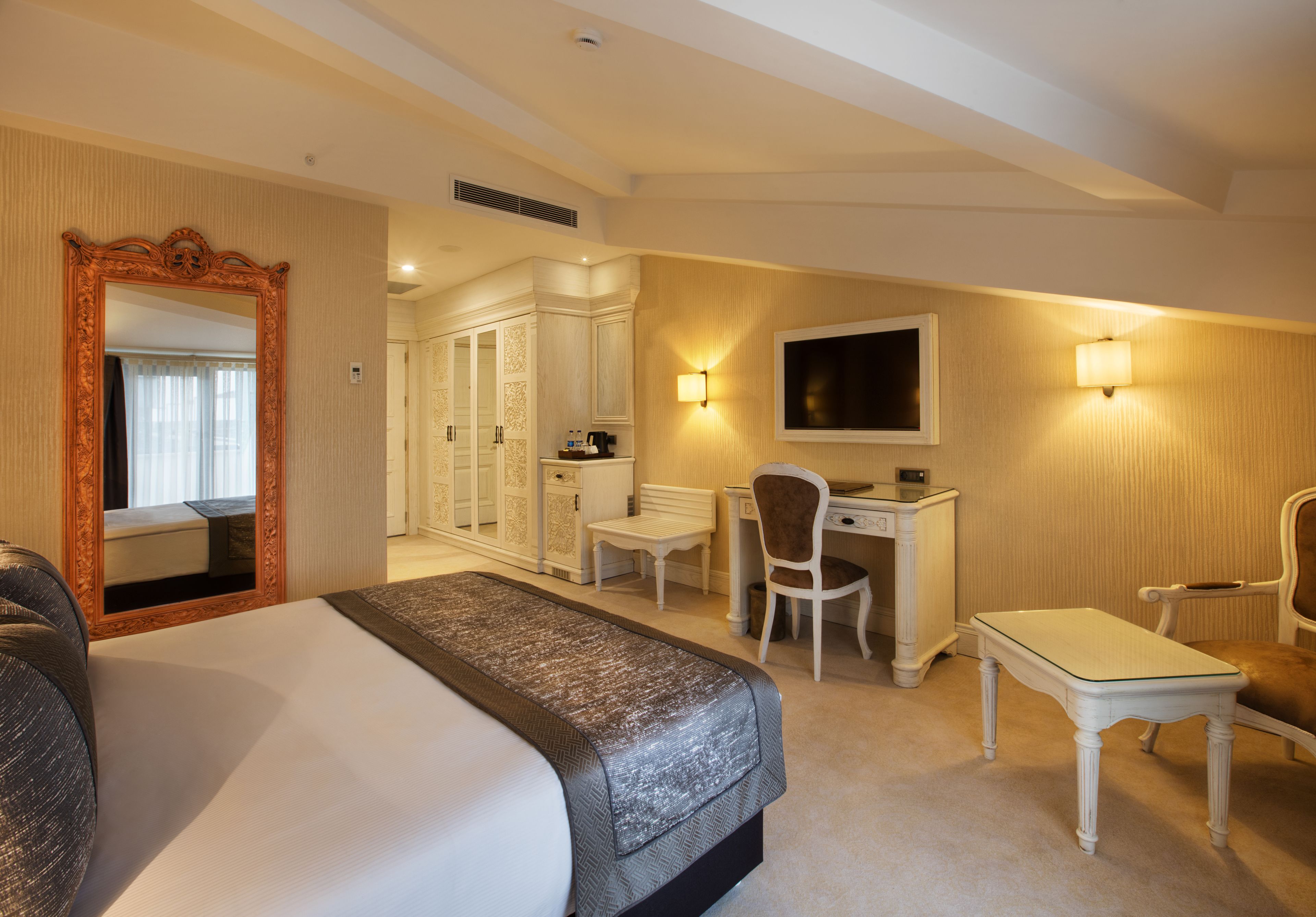 Een hotelkamer met een groot bed, een bureau, twee stoelen, een televisie en een kledingkast.