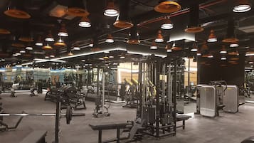 A gym with various exercise equipment, mirrors, and multiple ceiling lights.