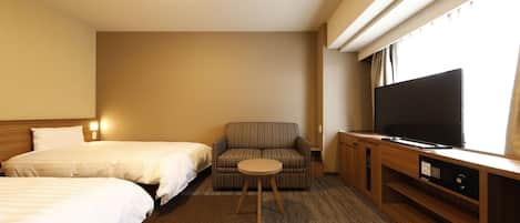 A hotel room with two beds, a sofa, a TV, and a small table.