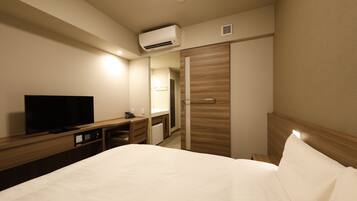A hotel room with a bed, a TV, a desk, and a wardrobe.