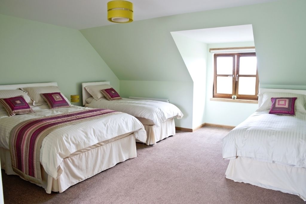 A bedroom with two beds, a window, and a yellow light fixture.