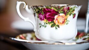 A white teacup with floral designs on a saucer.