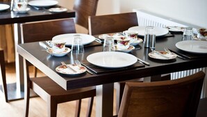 A dining table set with plates, cutlery, and glasses, surrounded by wooden chairs.