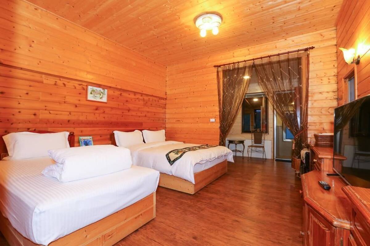 A wooden cabin with two beds, a TV, and a dining area.