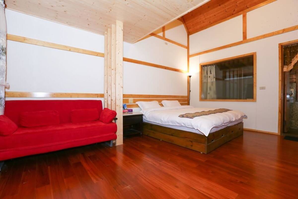 A bedroom with a wooden bed, a red sofa, and a nightstand.