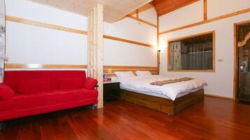 A bedroom with a wooden bed, a red sofa, and a nightstand.