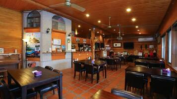 Un restaurante con interiores de madera, varias mesas y sillas, y una zona de bar.