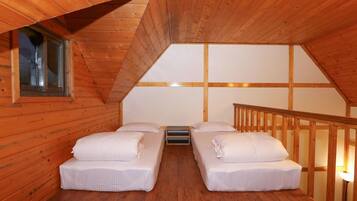Quarto de cabana de madeira com duas camas, uma janela e uma escada de madeira.