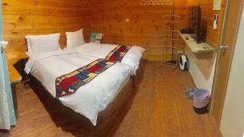 A wooden cabin room with a bed, a small table, a ladder, and a trash bin.