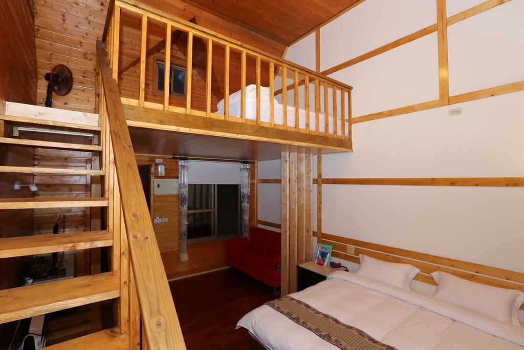 A bunk bed room with a wooden ladder, a red chair, and a bedside table with a book.