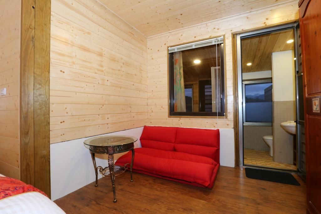 A compact room with wooden walls, a red sofa, a small round table, and a window.