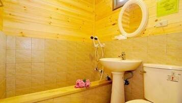 A bathroom with wooden walls, a white sink, a toilet, and a shower with a circular mirror.