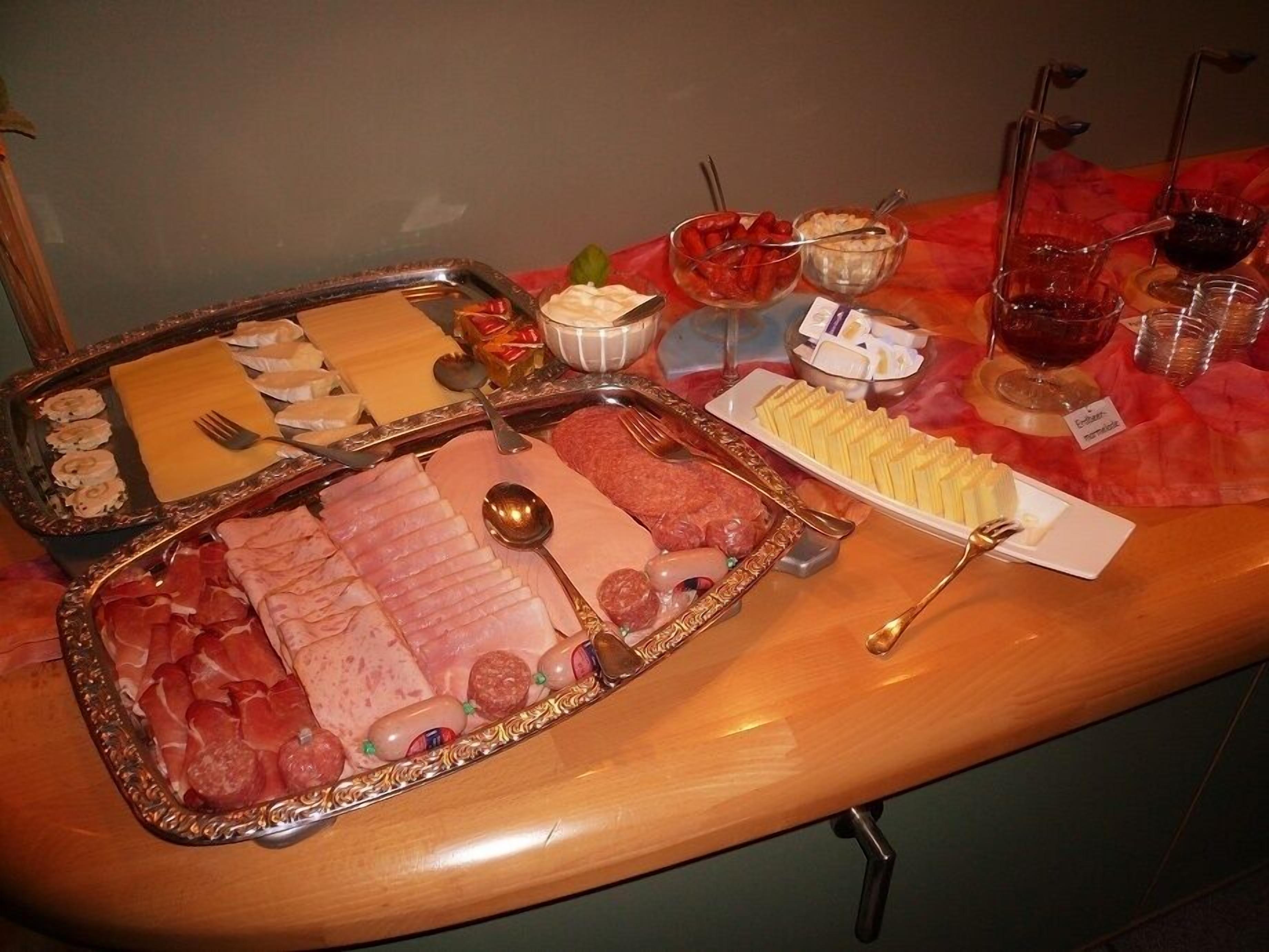 A buffet table with various food items including meats, cheeses, and desserts.