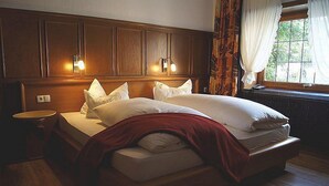 A double bed with a red blanket, wooden headboard, and two bedside lamps. - Hotel Rosenhaus Garni (Velbert)