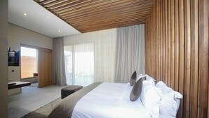 A modern bedroom with a large bed, wooden ceiling, and a view of the outdoors. - Palais Sohan (Oulad Hassoune)