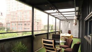 A balcony with a view of a building, a chair, a small table, and a potted plant. - YH GuestHouse - Hostel (Seoul)