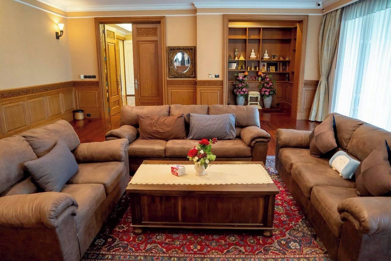 Un salon spacieux avec deux canapés en cuir marron, une table basse en bois et un tapis rouge à motifs.