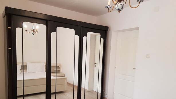 Een slaapkamer met een bed, een kast en een spiegel.
