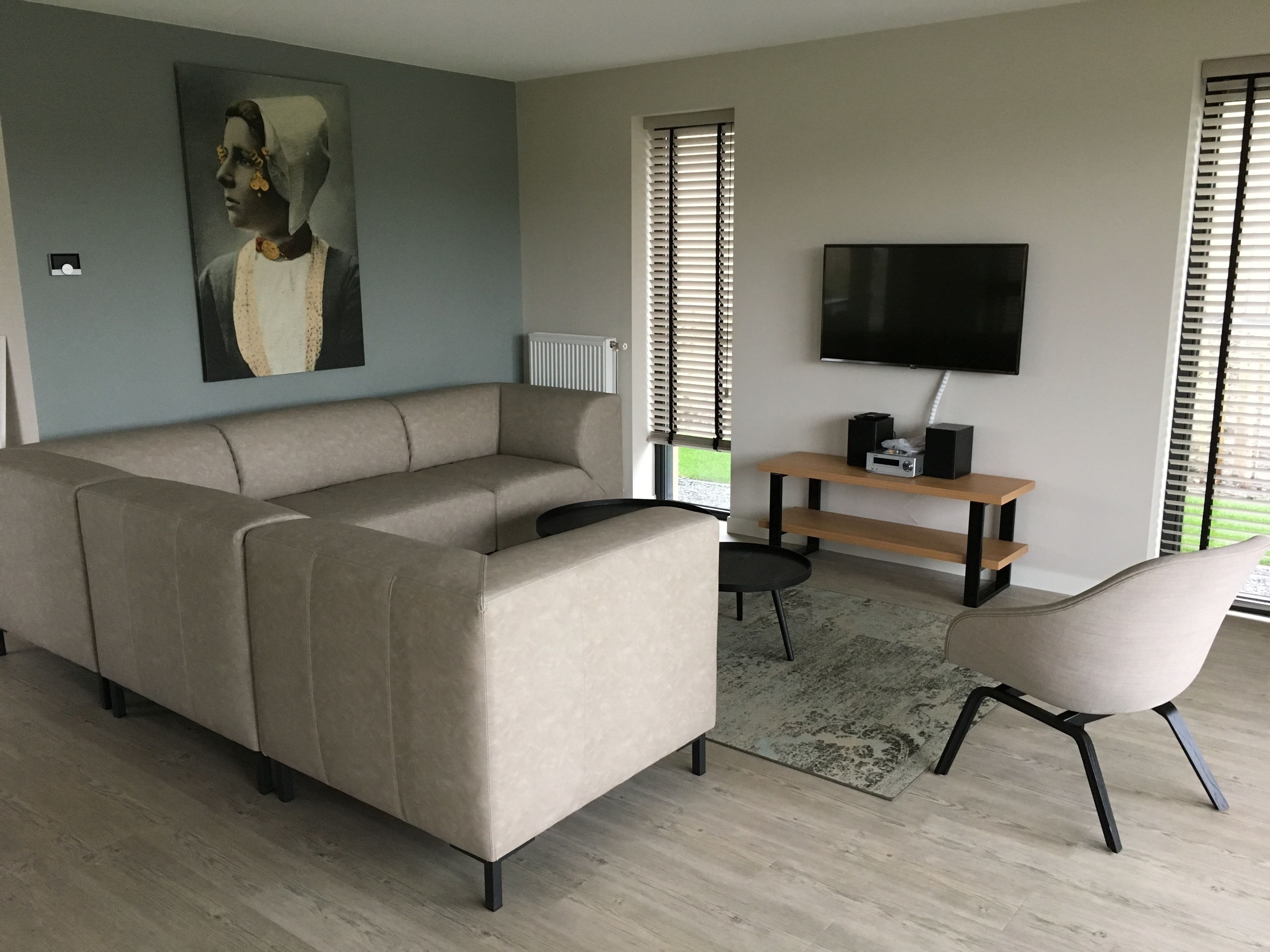 Un salon moderne avec un canapé d’angle, un téléviseur et une petite table.