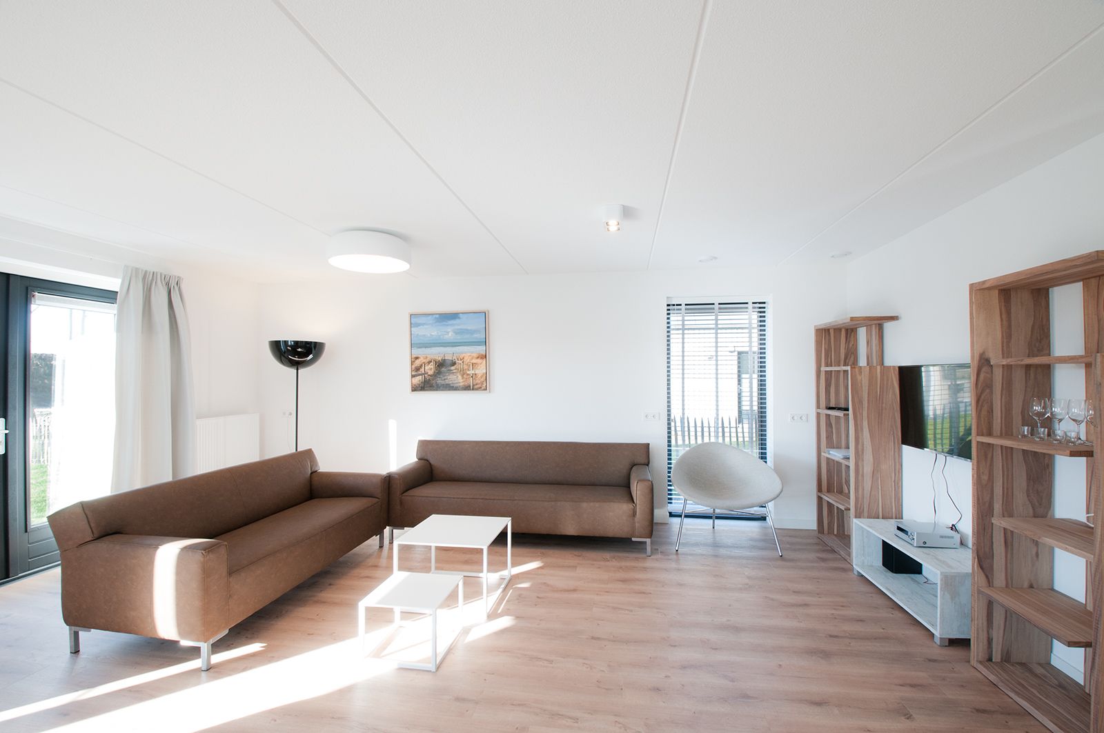 A modern living room with a brown sectional sofa, a white coffee table, and a wooden TV stand.