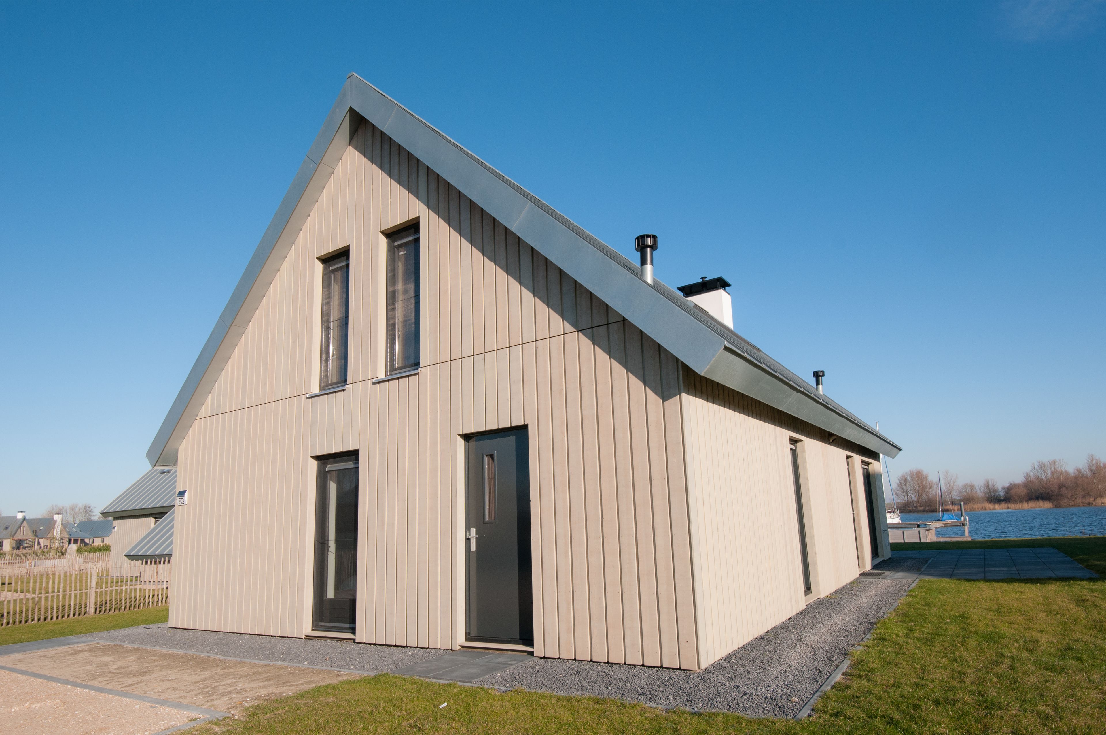 Un bâtiment moderne, de plain-pied, doté d’un toit en pente, d’une grande porte et d’une fenêtre.