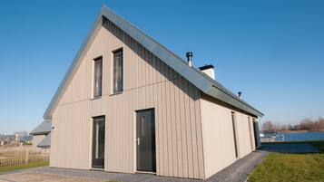 Un bâtiment moderne, de plain-pied, doté d’un toit en pente, d’une grande porte et d’une fenêtre.