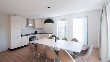 A modern kitchen with white cabinets, a dining table with chairs, and a pendant light.