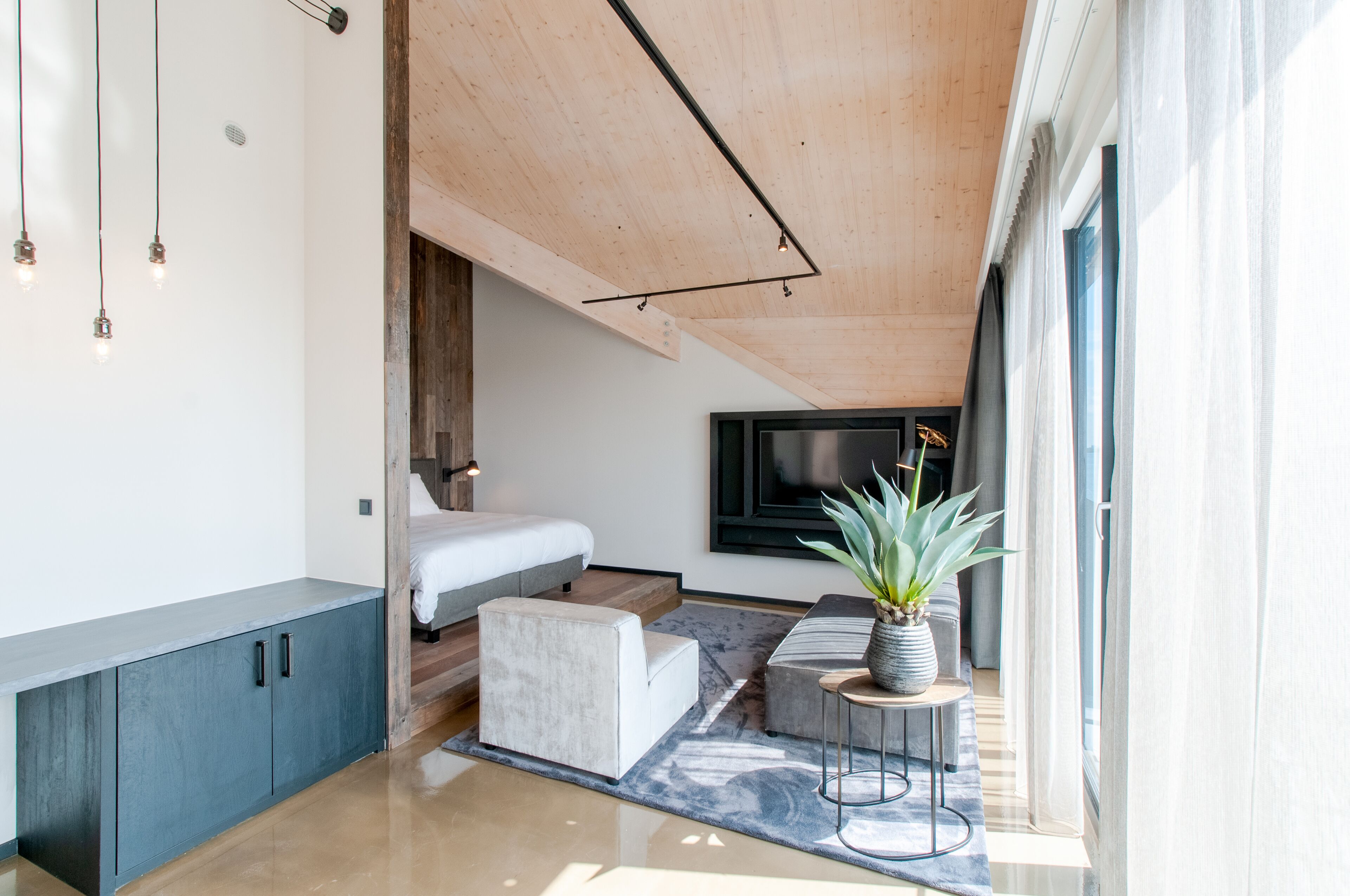 A modern bedroom with a bed, bedside table, and a TV mounted on the wall.