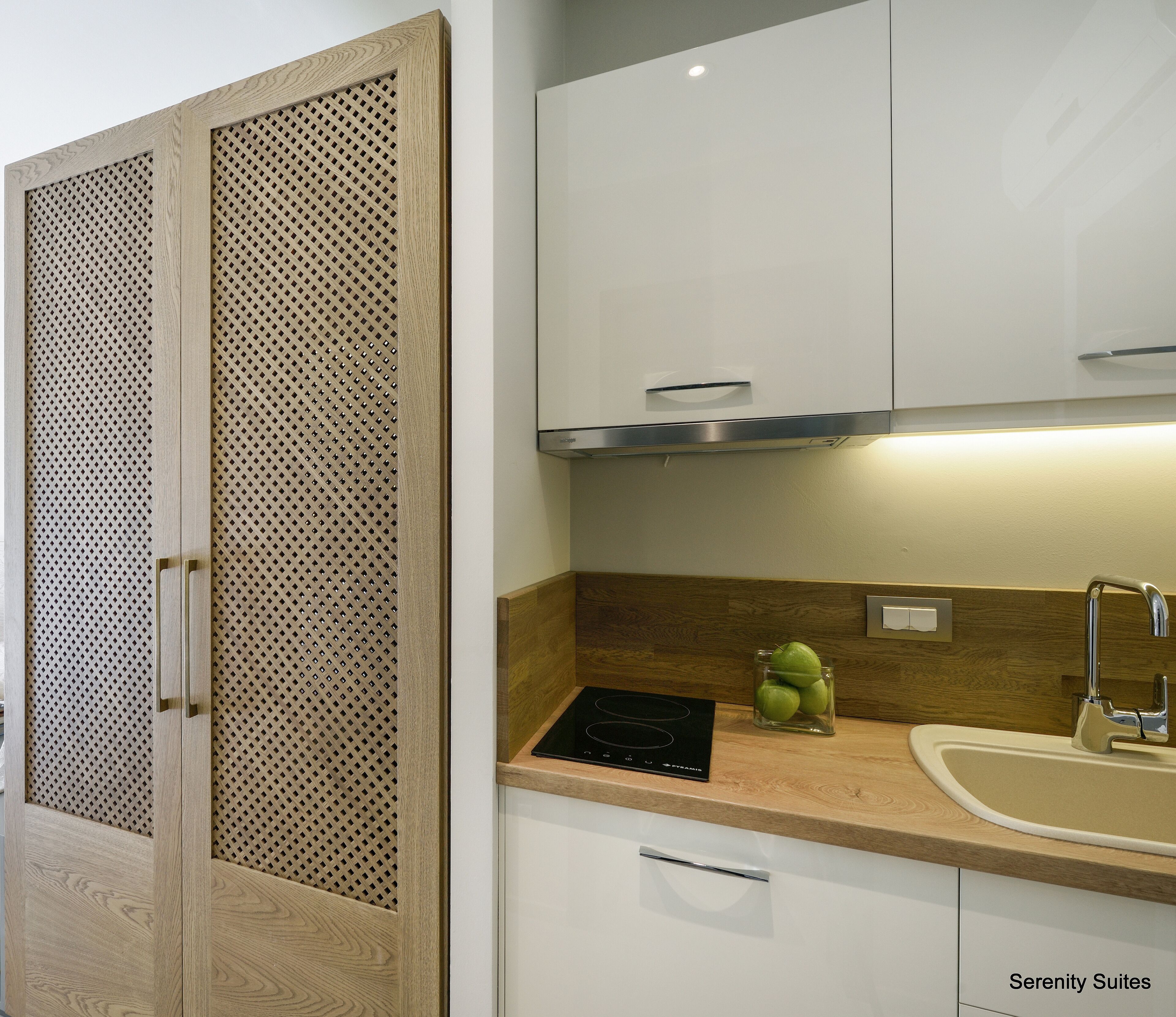Une cuisine avec des meubles de rangement en bois, une cuisinière encastrée et un évier.