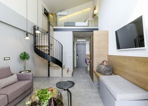 Un interior moderno con una escalera, un sofá, una mesa de centro y un televisor montado en la pared.