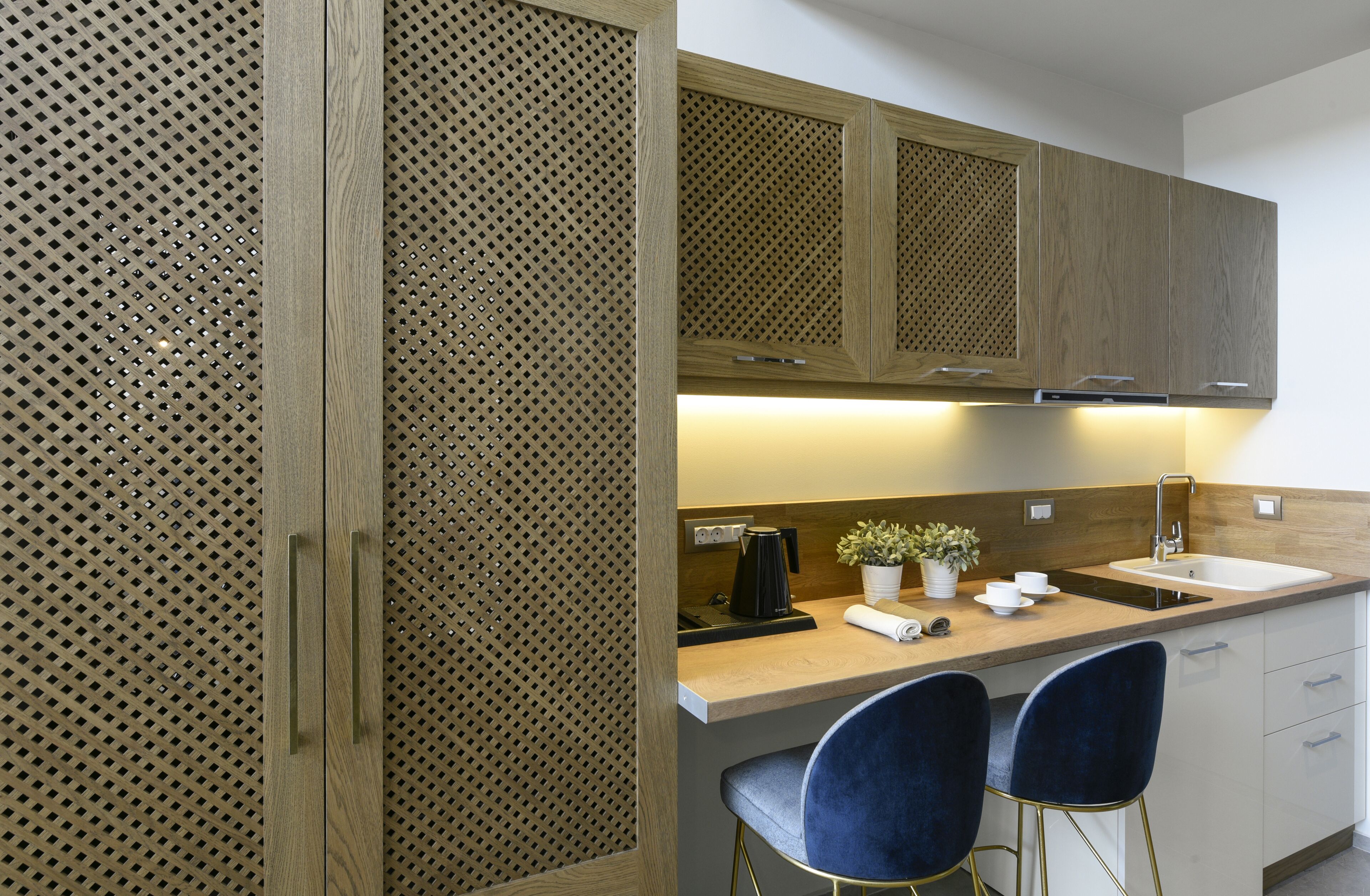 A modern kitchen with wooden cabinets, a countertop, two bar stools, and a sink.