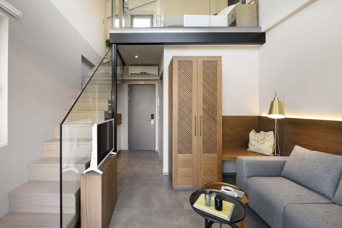 Un apartamento moderno con una escalera, un sofá, una mesa de centro y una lámpara.