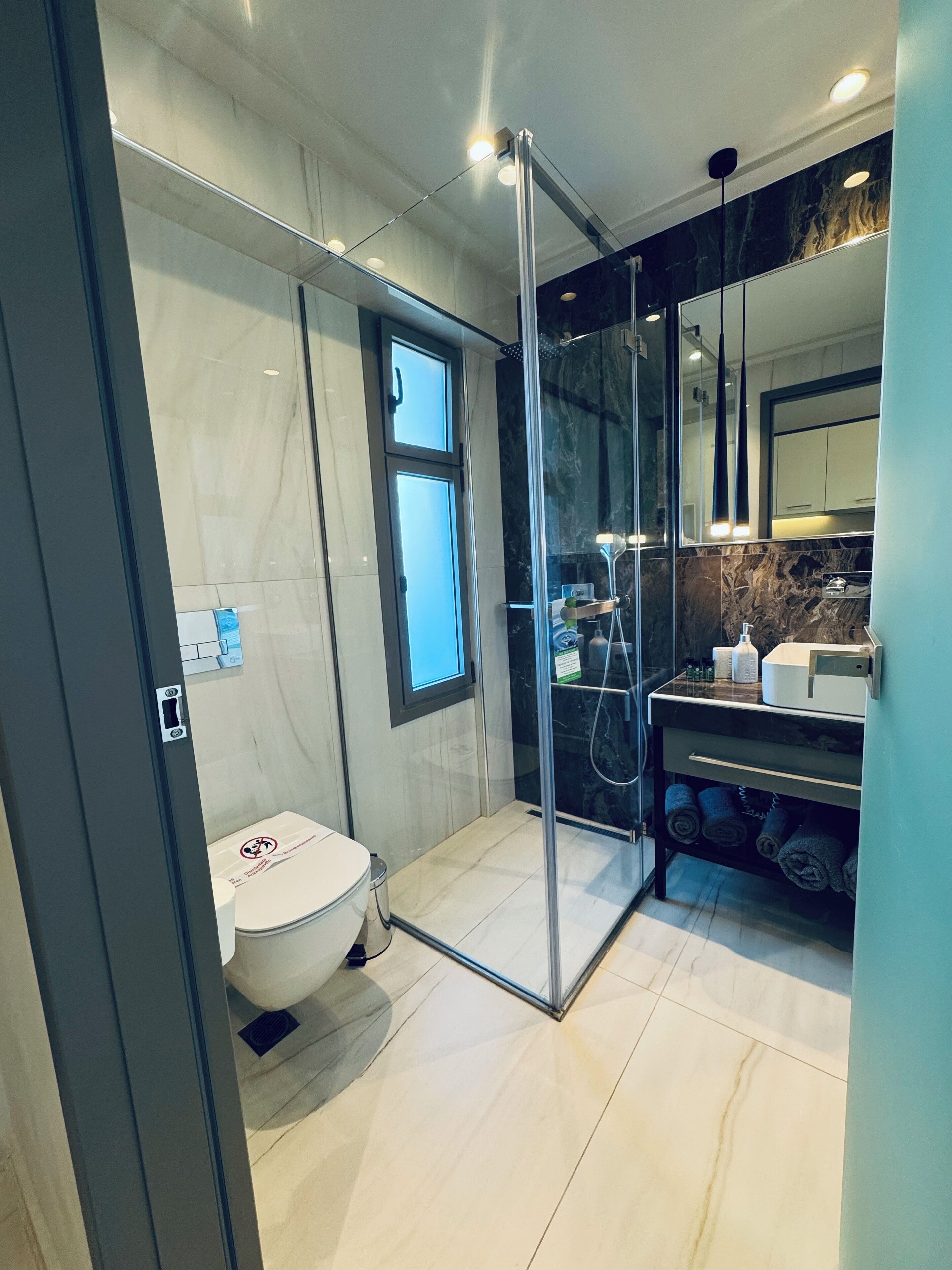 Un baño moderno con ducha de vidrio, inodoro y tocador con encimera de mármol.