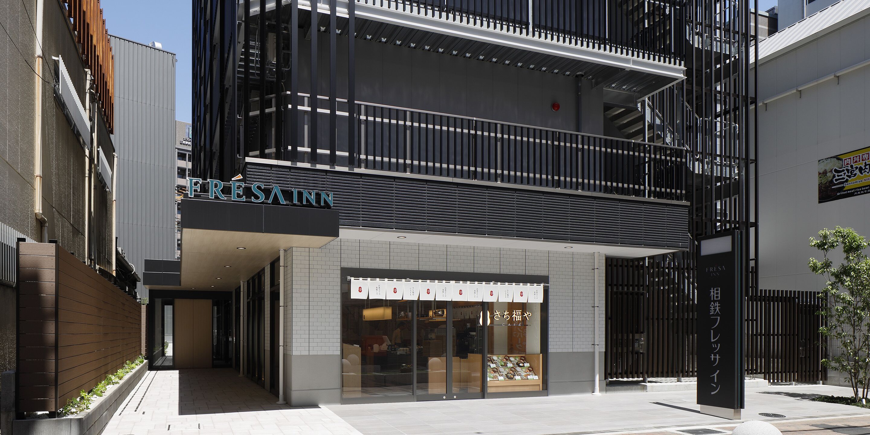 Un edificio moderno con un letrero que dice 'FRESA INN' y un restaurante japonés.