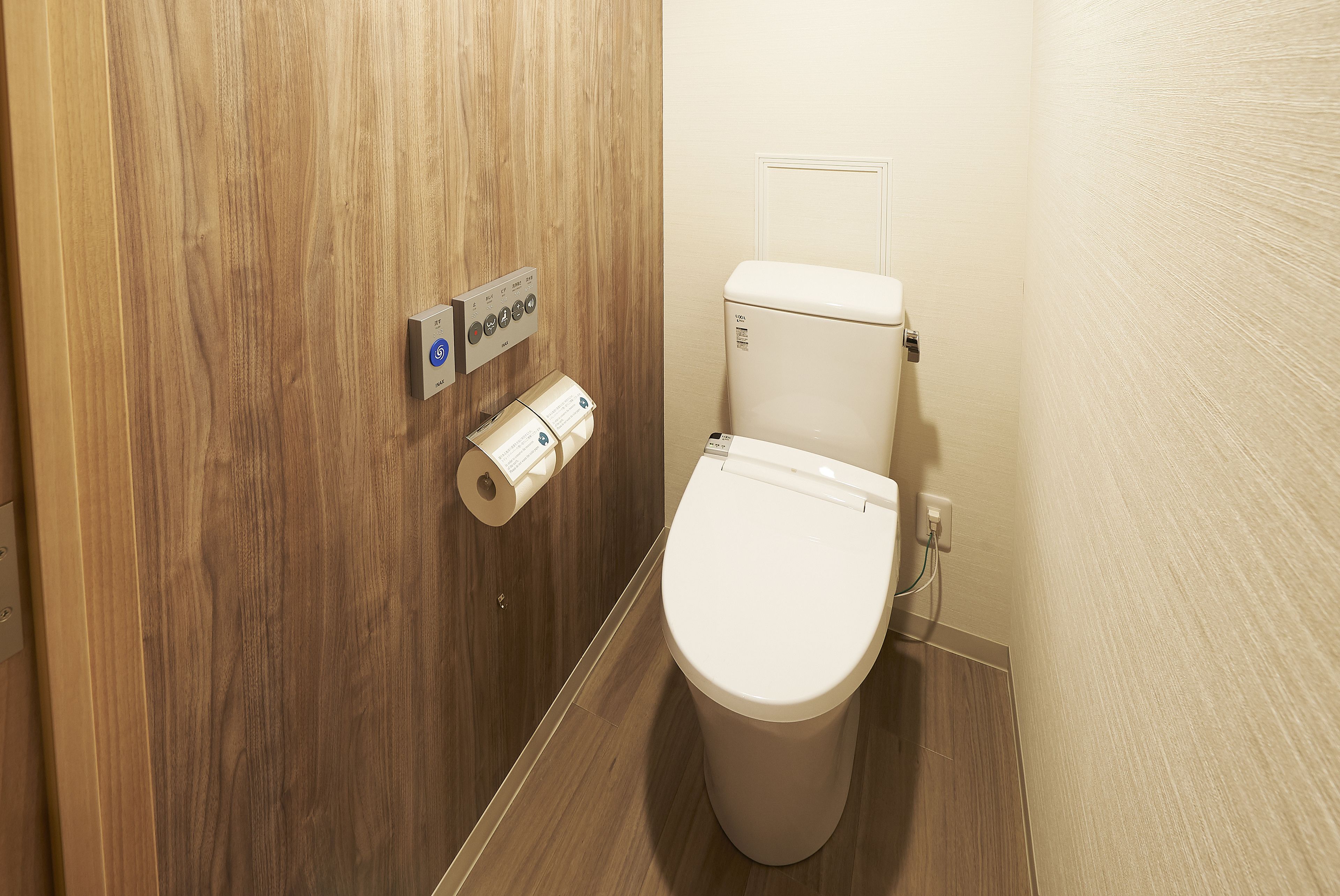 A bathroom with a wooden door, a toilet, and a paper towel dispenser.