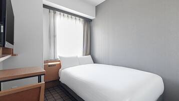 A hotel room with a bed, a desk, a chair, a window with curtains, and a television.