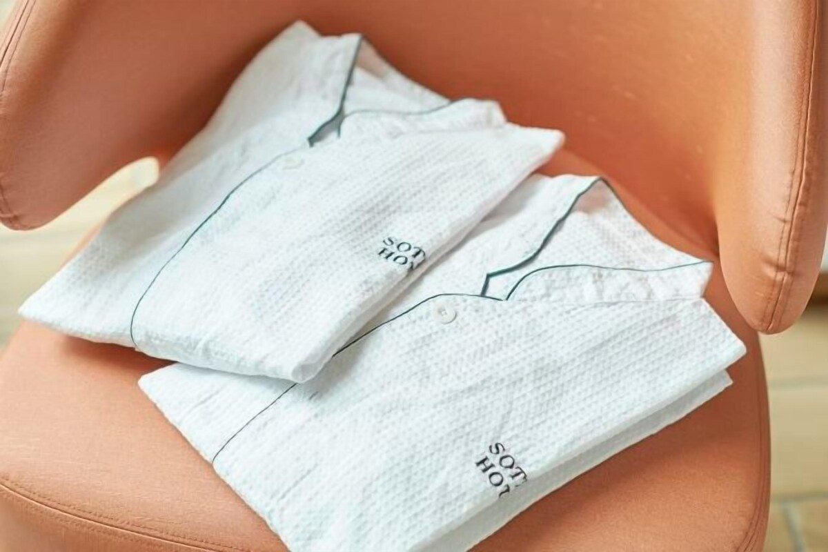 A white shirt with "SON HOT" printed on it, placed on a brown leather chair.