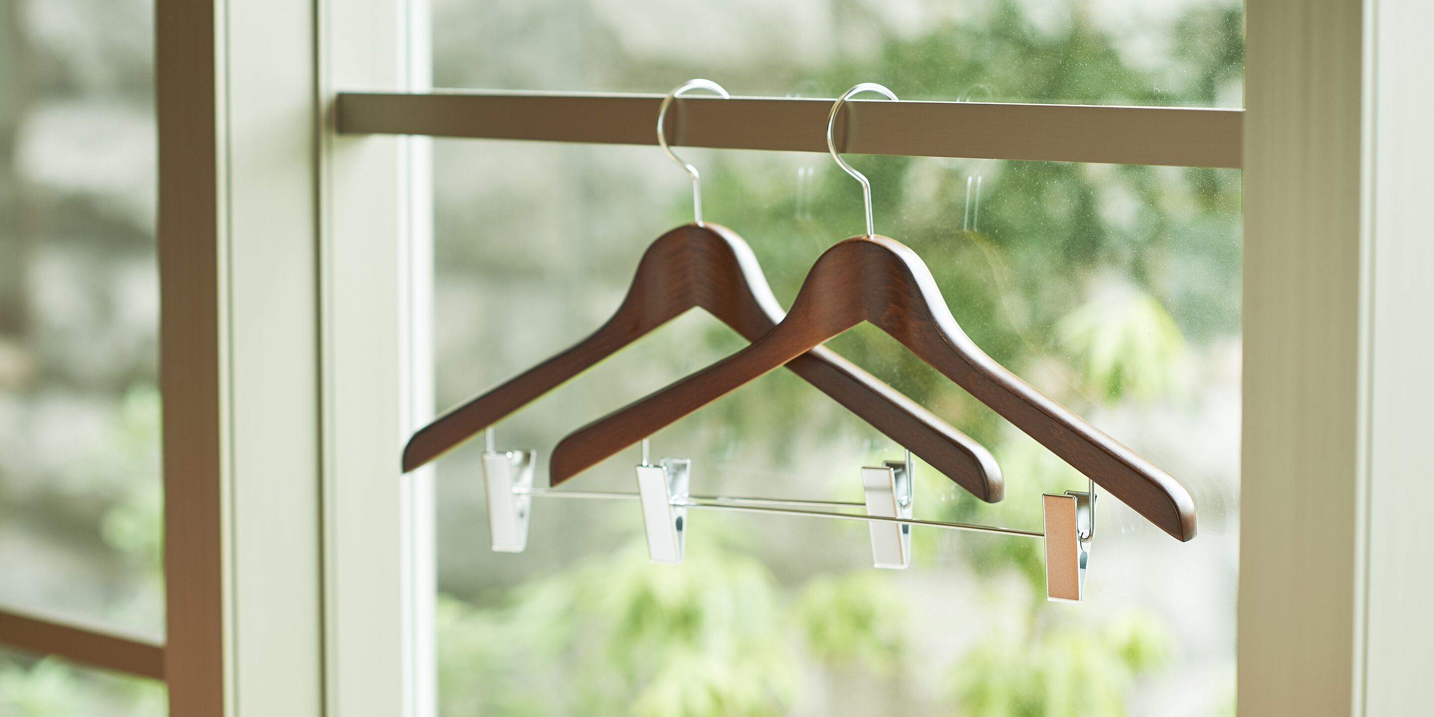 A window with wooden hangers on a metal rack.