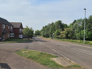 A residential street with houses, a clear sky, and a pedestrian crossing. - Huku Kwetu - Ravenhill House (Luton)