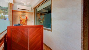 Un mostrador de recepción con ventilador de techo, unidad de aire acondicionado e ícono religioso enmarcado encima.