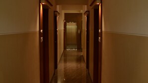 Un pasillo con puertas a ambos lados que conduce a una habitación con un gran ventanal.