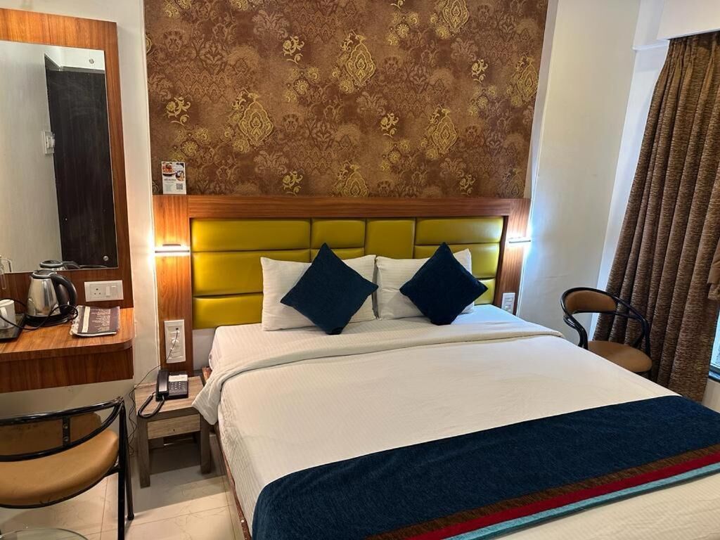 A hotel room with a bed, a desk with a telephone, and a chair.