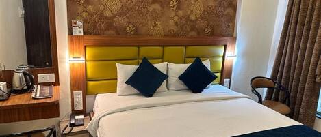 A hotel room with a bed, a desk with a telephone, and a chair.