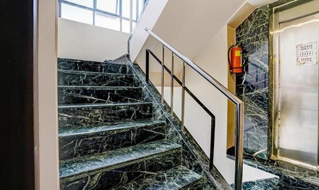 A staircase with a handrail and a fire extinguisher mounted on the wall.